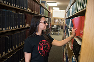 Student chooses book from shelf at NIU Law Library